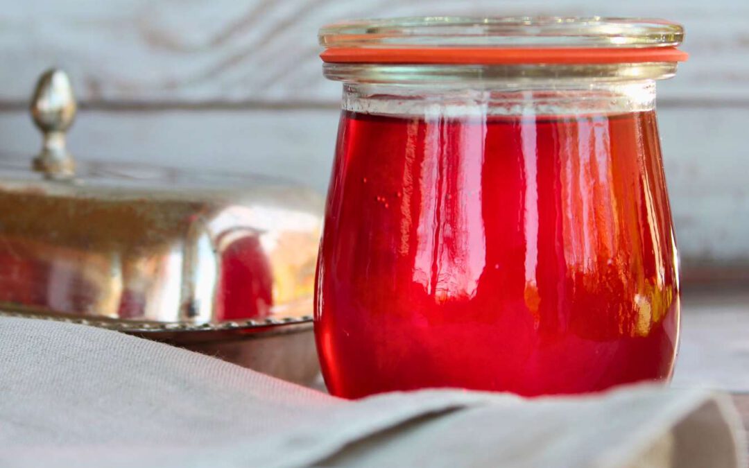 Erdbeer-Gelee im Weckglas, im Gegenlicht fotografiert – leuchtend rot mit schöner Spiegelung