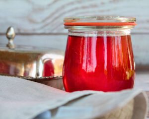 Erdbeer-Gelee im Weckglas, im Gegenlicht fotografiert – leuchtend rot mit schöner Spiegelung