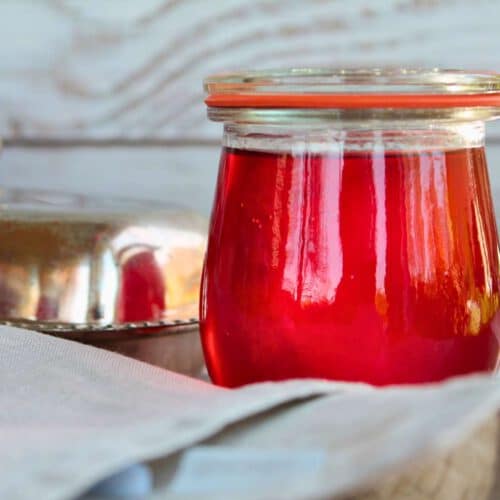 Erdbeer-Gelee im Weckglas, im Gegenlicht fotografiert – leuchtend rot mit schöner Spiegelung
