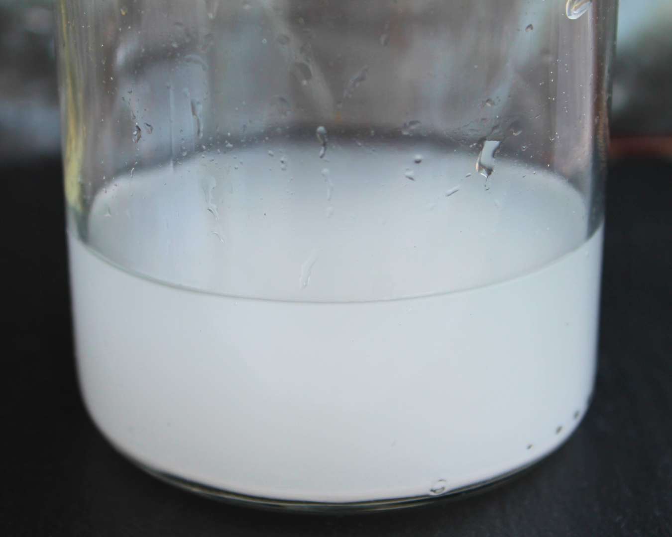 Weißlich-trübe Flüssigkeit in einem Glas – frisch angerührtes Calciumwasser für die Verwendung mit Pomona’s Pektin.