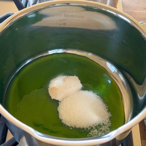 Zucker und Pektin werden in flüssiges, nicht geliertes Gelee eingerührt, um es nachzukochen.