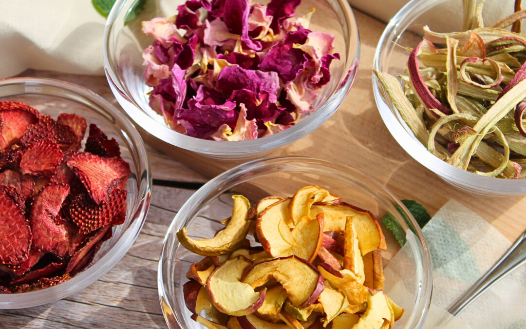 Getrocknete Zutaten für DIY-Rhabarbertee: Rosenblätter, Erdbeeren, Apfel und Rhabarber in Glasschalen