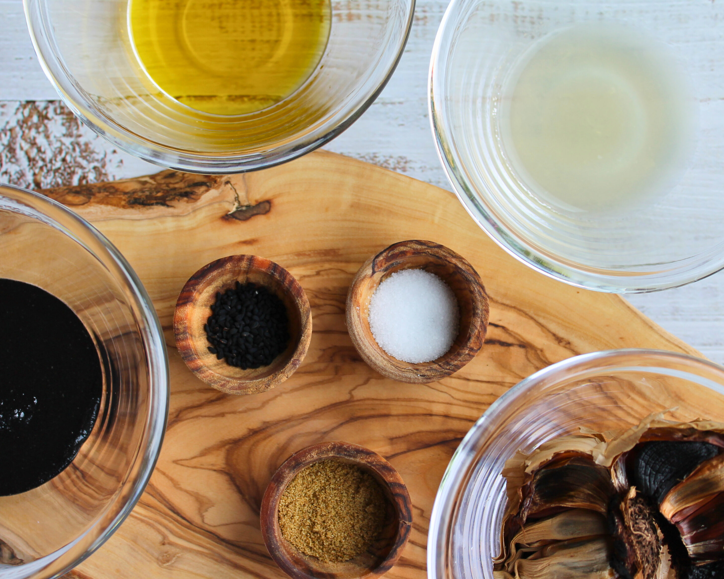 hummus-zutaten-schwarzer-knoblauch-schwarzkümmel-olivenoel.jpg Zutaten für Hummus aus schwarzen Kichererbsen: schwarzer Knoblauch, Kreuzkümmel, Schwarzkümmel, Salz, Olivenöl und Zitronensaft dekorativ angerichtet.
