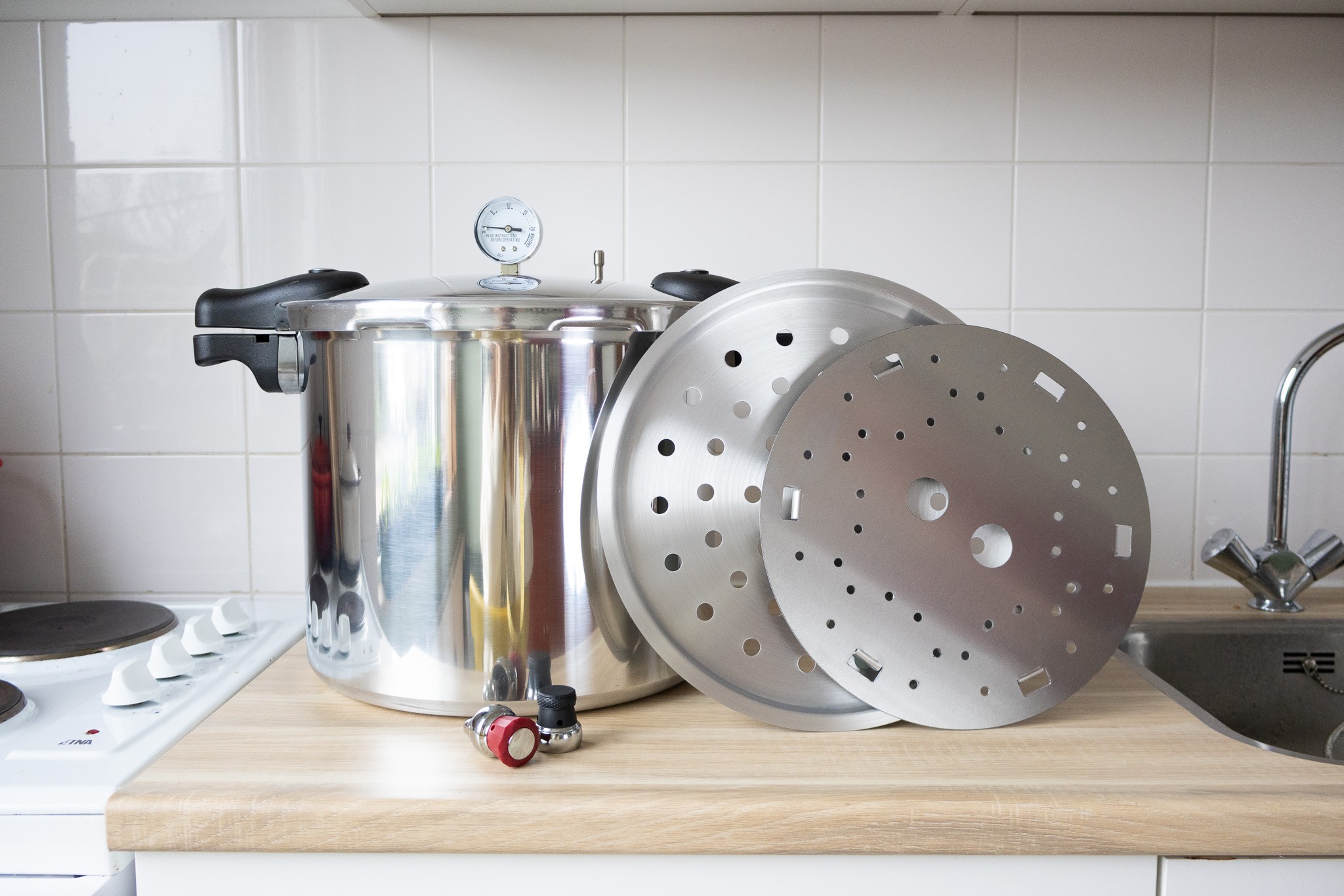 canmate-press-pan-22qt-mit-zubehoer.jpg CanMate Press Pan 22QT Pressure Canner mit Manometer, Griffen, Rosten und Gewichten auf einer Küchenarbeitsplatte