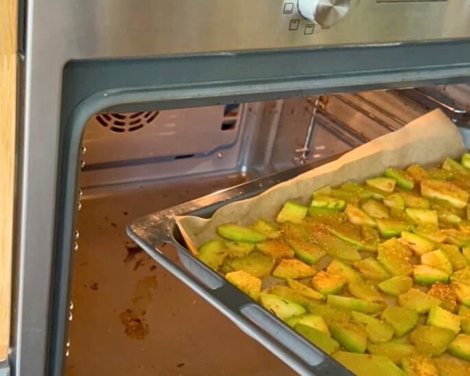 zucchini-im-backofen-trocknen.jpg Zucchinischeiben auf einem Blech mit Backpapier werden im Umluftofen bei niedriger Temperatur getrocknet.
