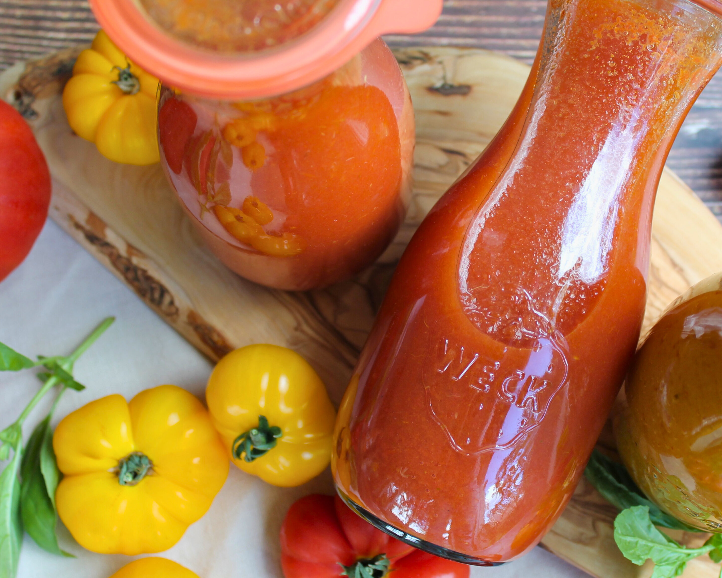 Selbstgemachte Tomatensauce in einer Weckflasche, dekoriert mit gelben und roten Tomaten.