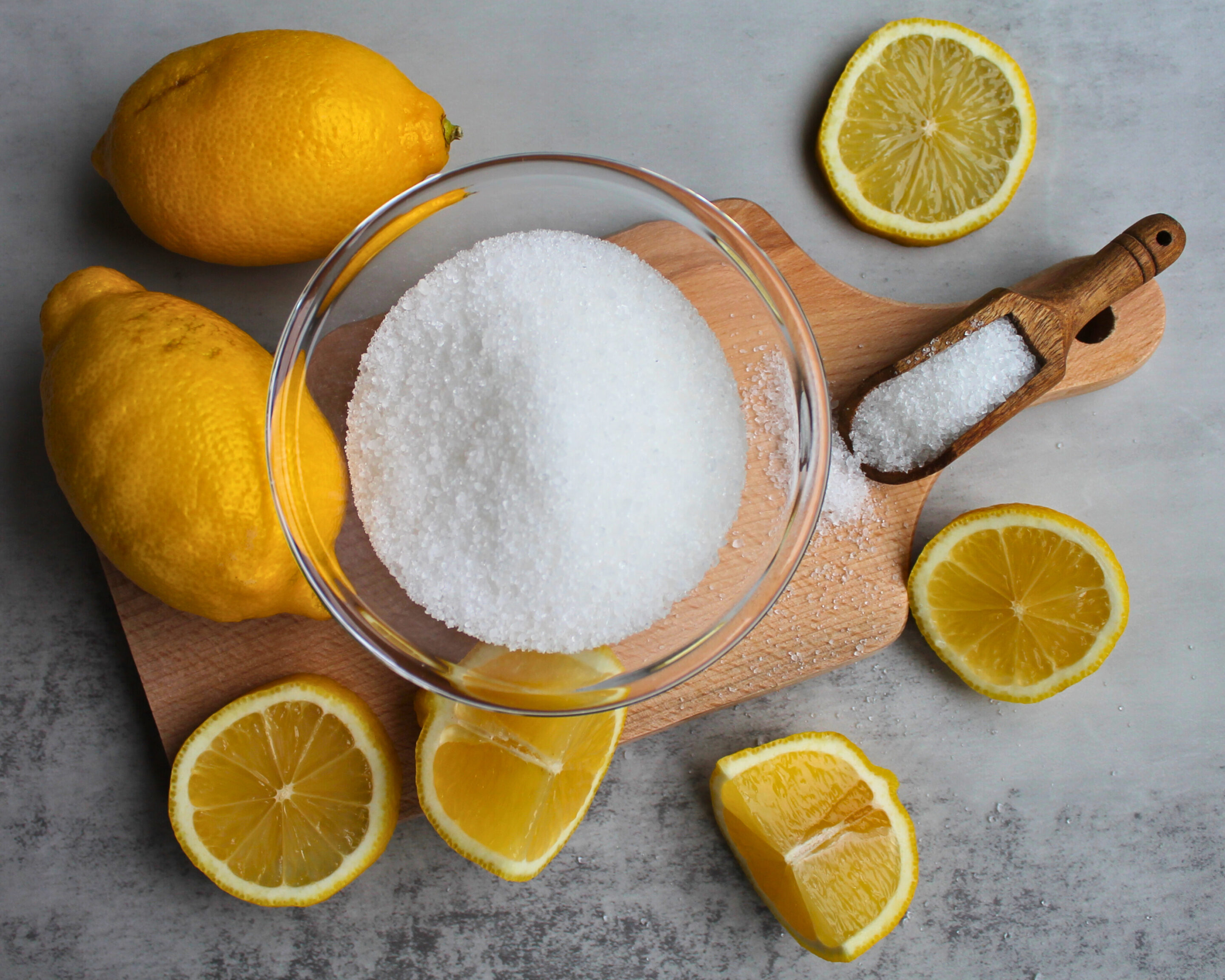 Detailaufnahme von Zitronensäure in einer Holzschaufel mit frischen Zitronen – Alternative zu Zitronensaft beim Einkochen.