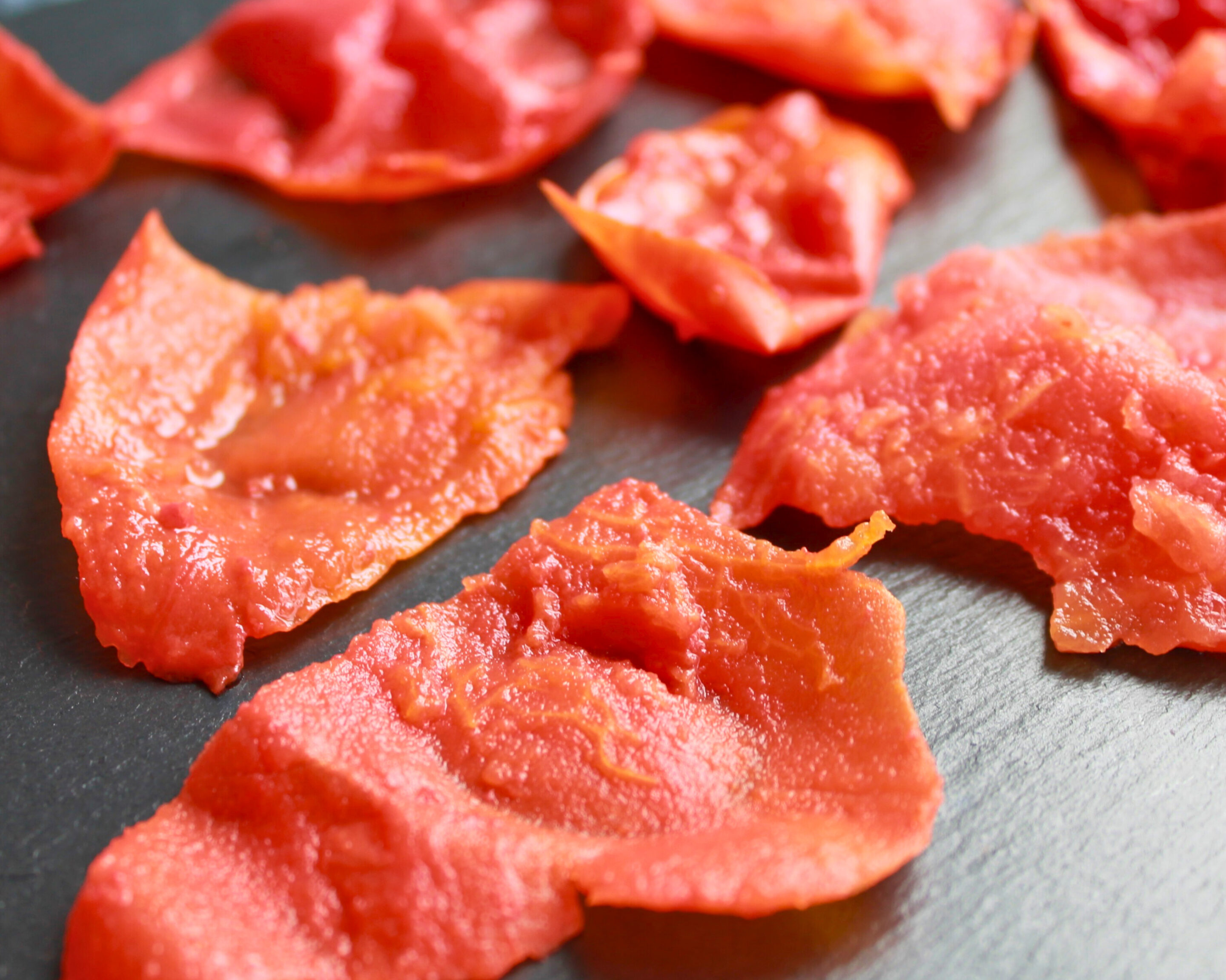 Frische Tomatenhaut auf dunkler Schieferplatte nach dem Häuten der Tomaten