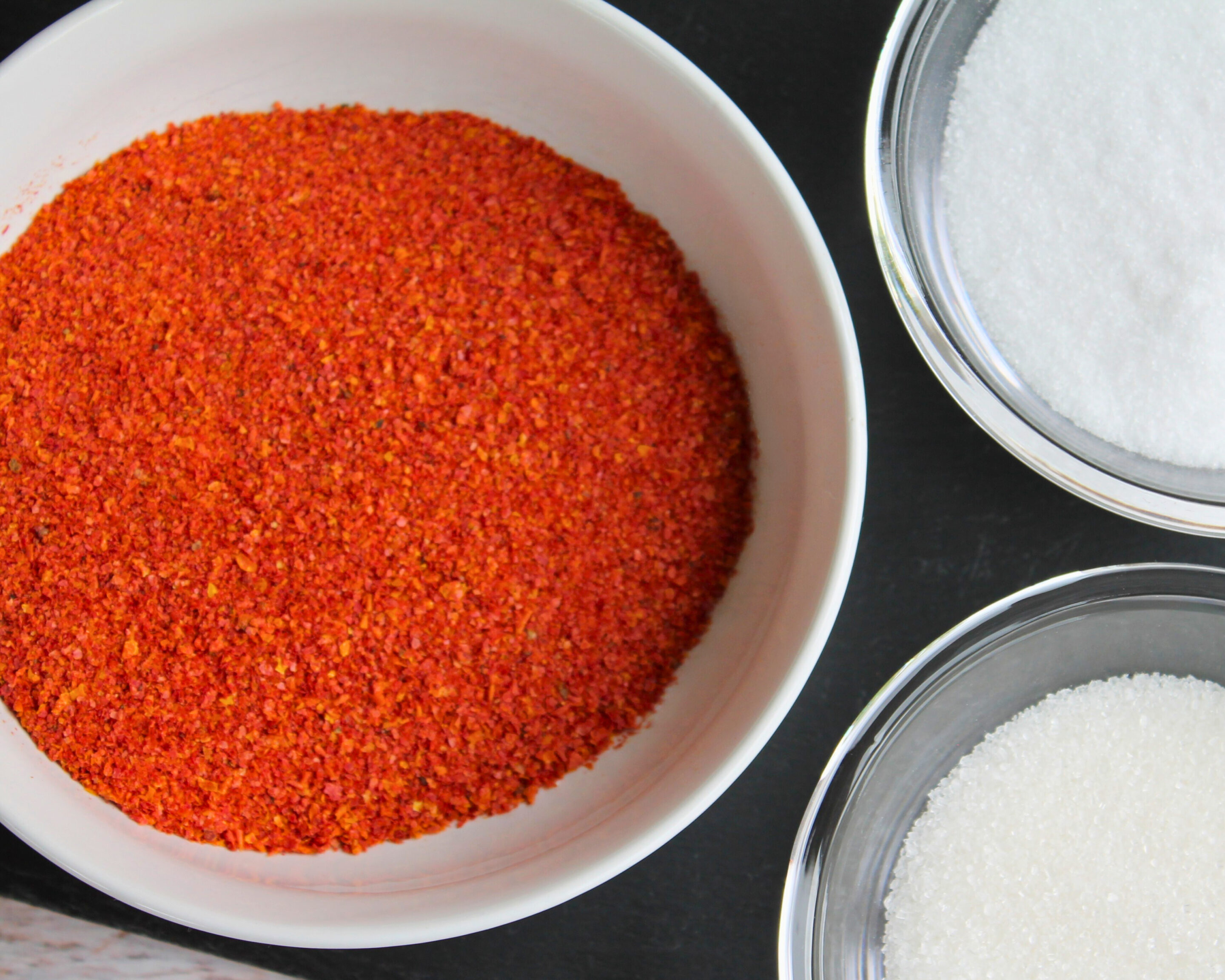 Schale mit Tomatenpulver neben Zucker und Salz – Grundlage für Tomatensalz oder Tomatenzucker