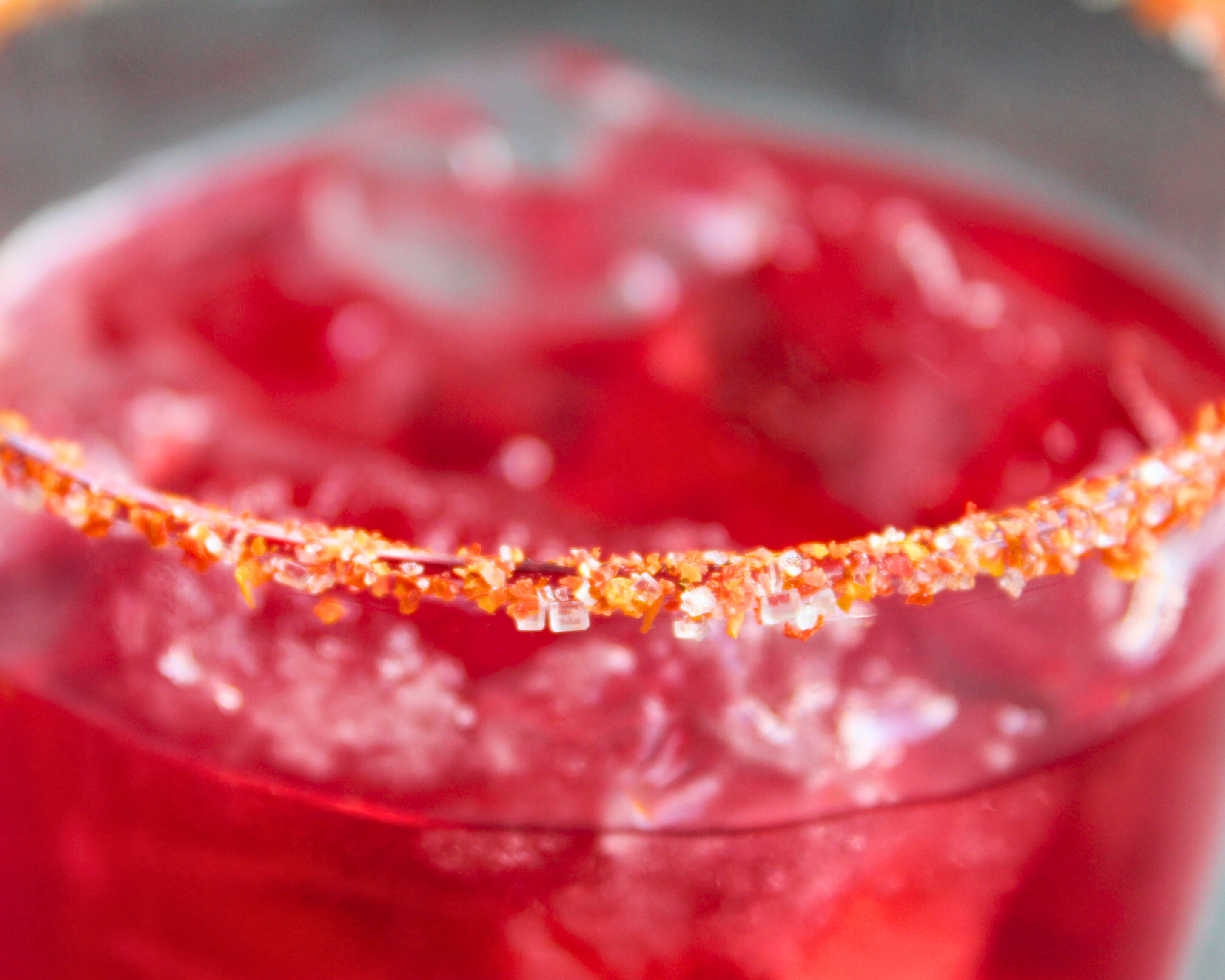Detailaufnahme von Tomatenzucker am Glasrand mit rotem Drink