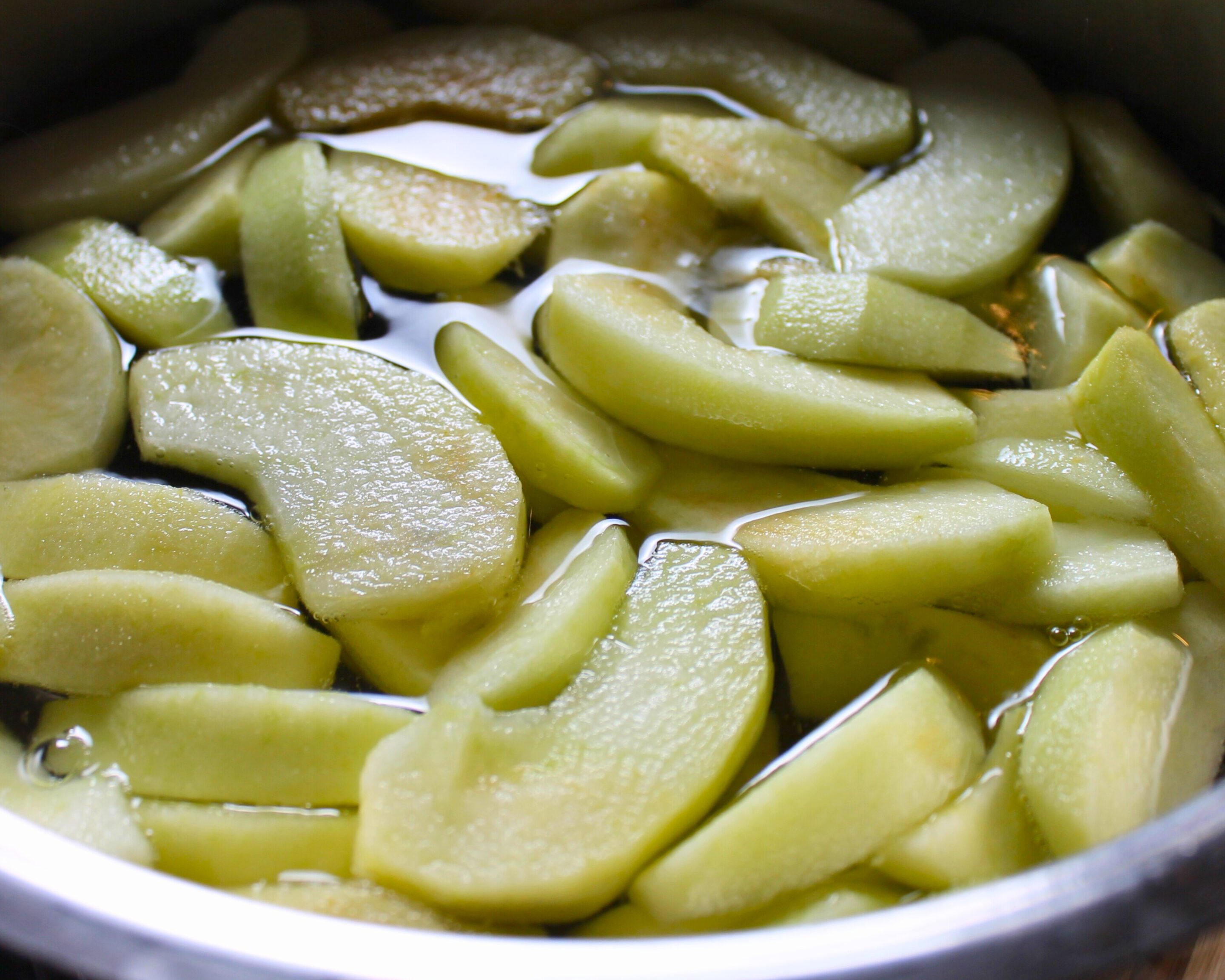 Frisch geschälte Apfelscheiben in Wasser mit Vitamin C, um Bräunung zu verhindern – Vorbereitung zum Einkochen.