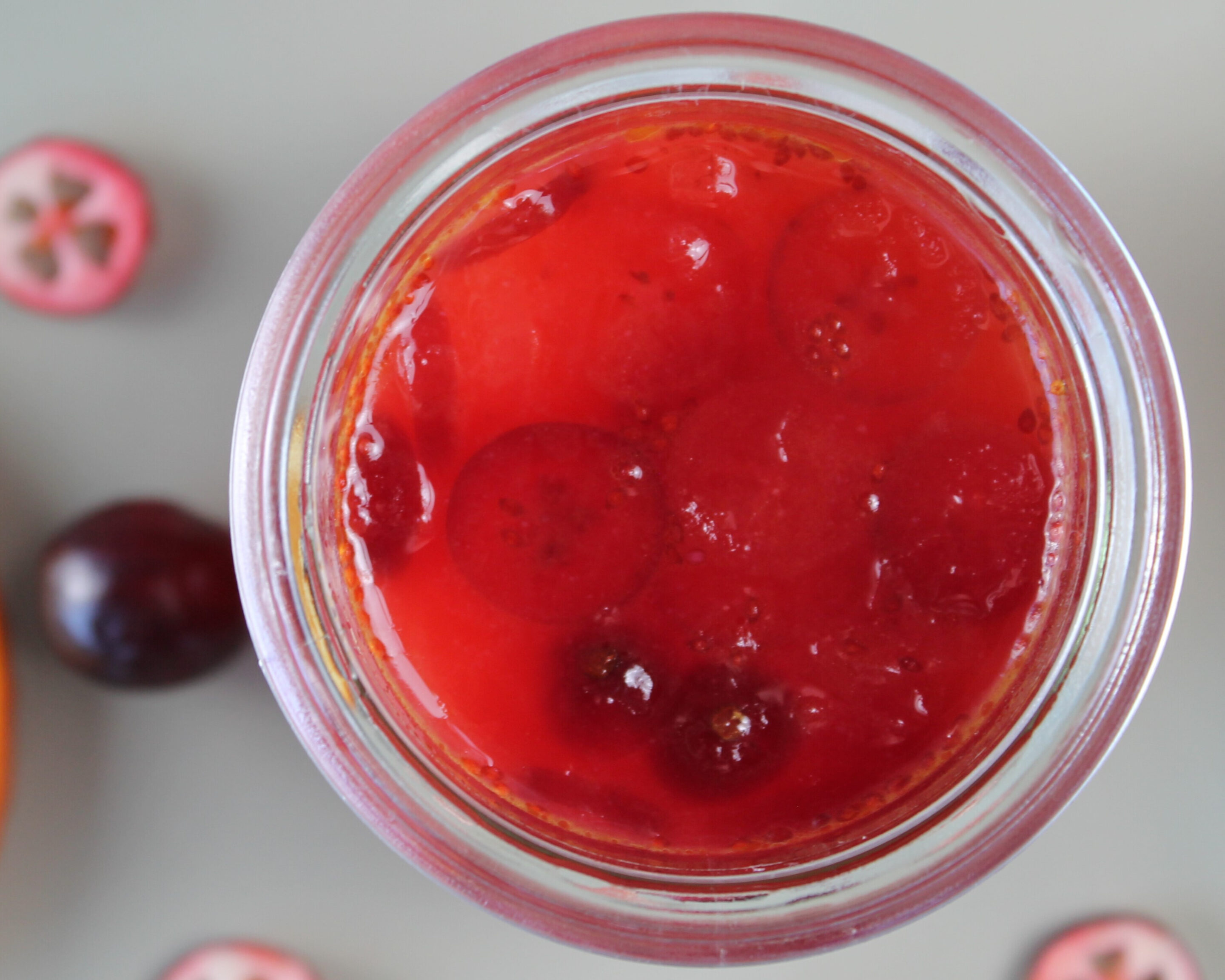 Selbstgemachte Cranberry-Orangen-Gelee im Glas von oben fotografiert – leuchtend rote Winterfüllung als Geschenk aus der Vorratskammer.