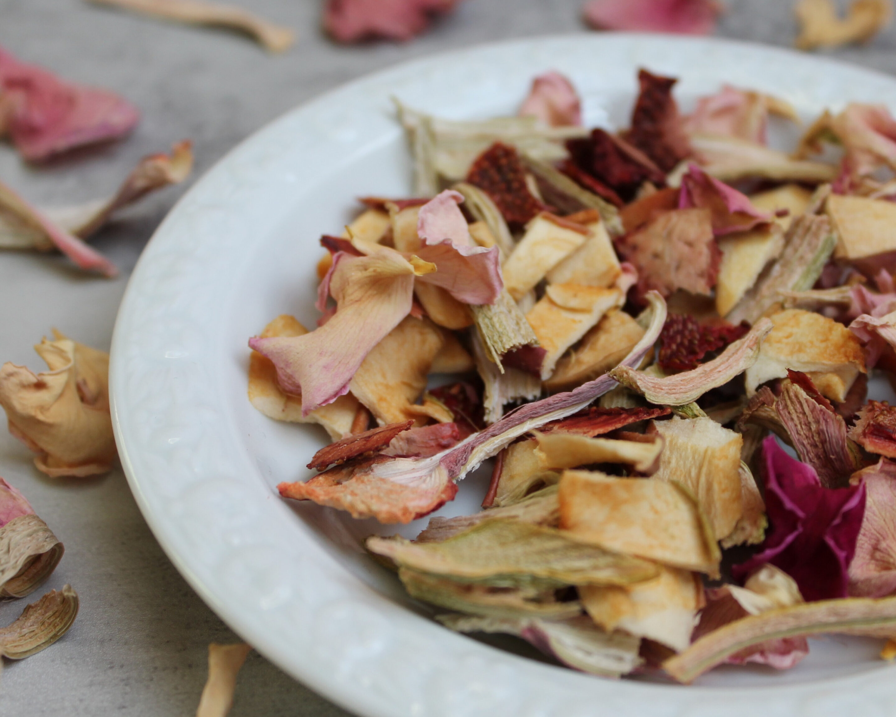 Getrocknete Früchte und Blüten auf einem Teller als einfache DIY-Geschenkidee aus haltbar gemachtem Obst.
