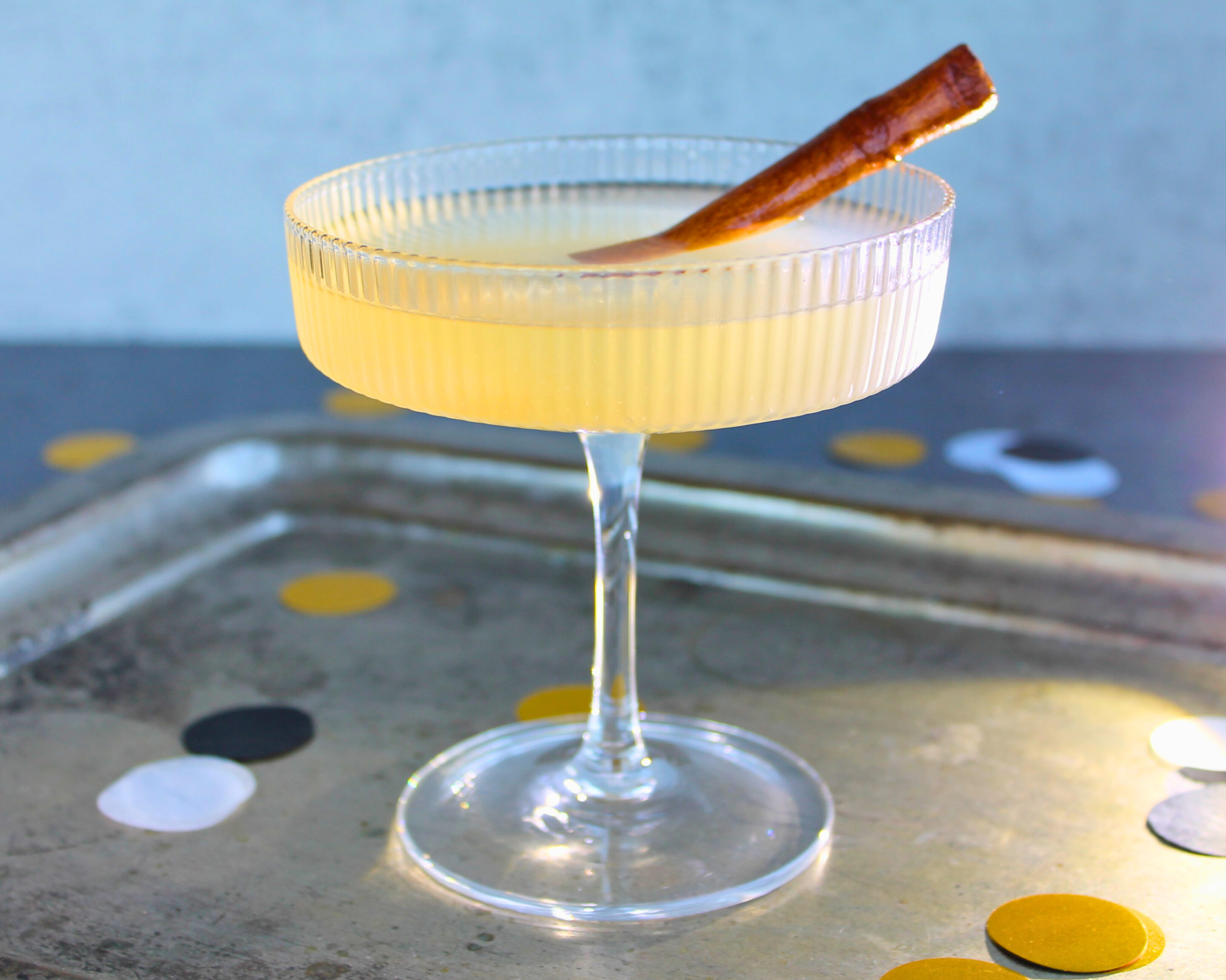 Alkoholfreier Golden Spice Mule mit Aprikosenmarmelade in geriffelter Sektschale, garniert mit Zimtstange