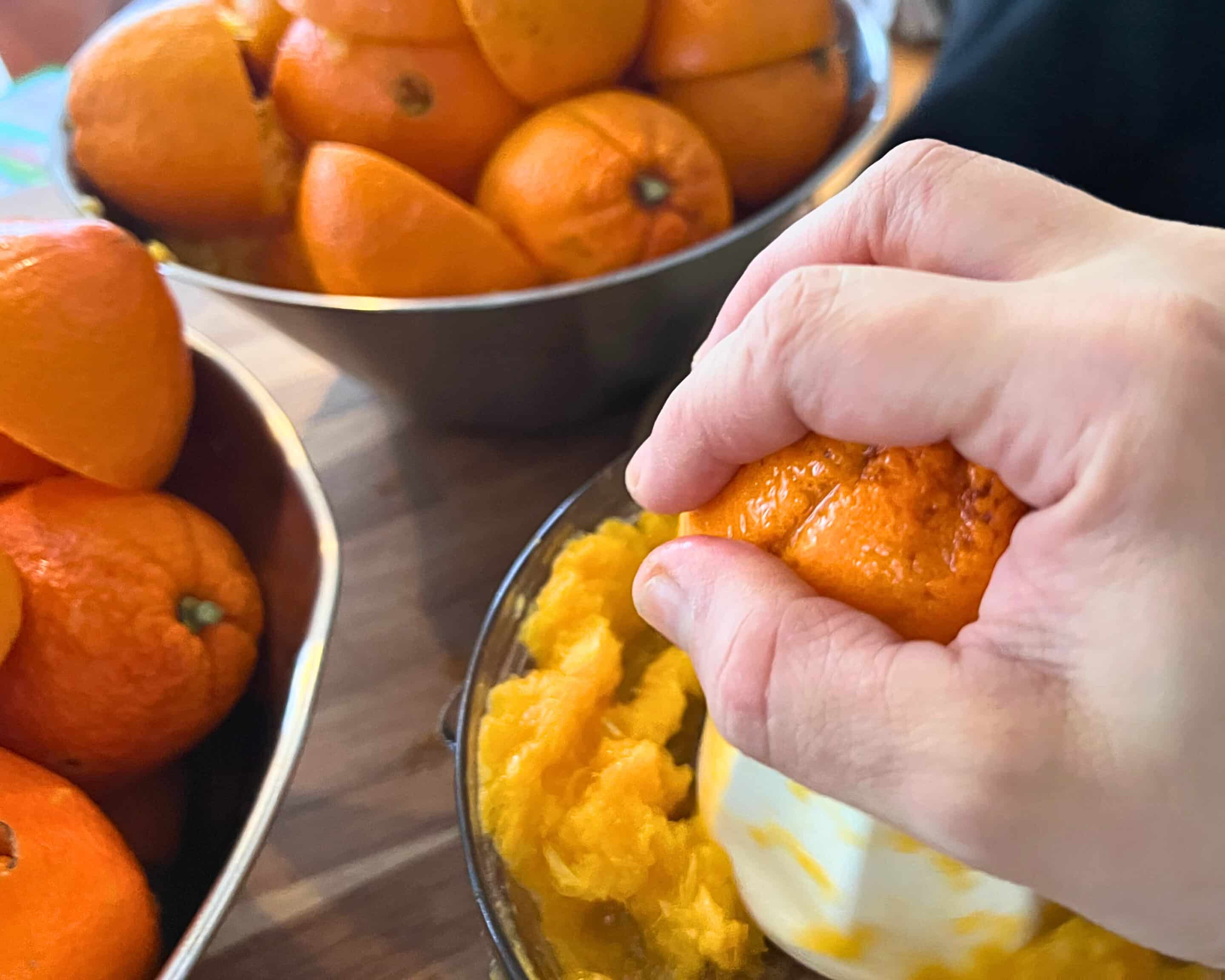 Orangen werden von Hand ausgepresst, um frischen Saft für das Einkochen im Wasserbad zu gewinnen.