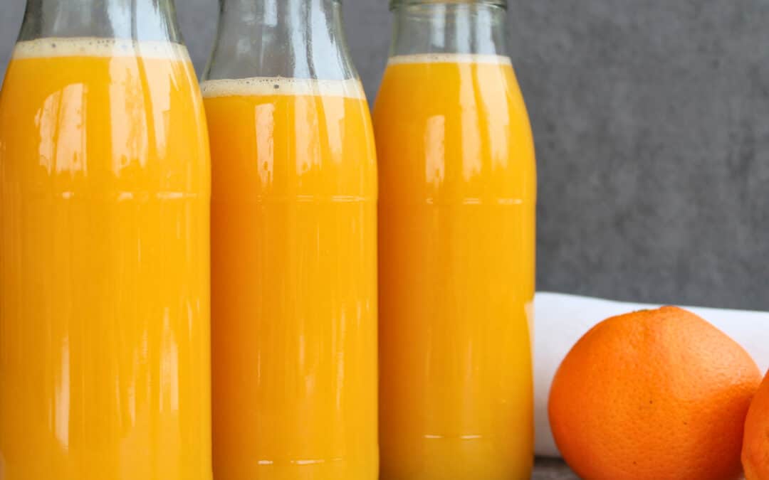 Drei Flaschen mit selbst eingekochtem Orangensaft ohne Zusatzstoffe, im Wasserbad haltbar gemacht – frischer Orangensaft im Glas als Vorrat für den Winter.