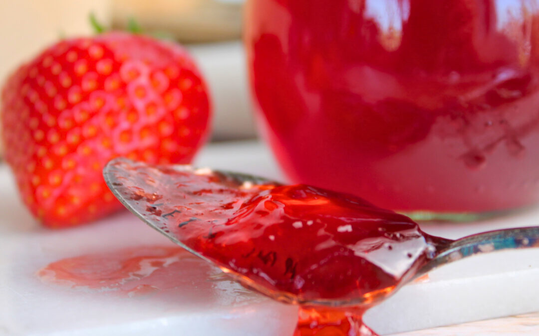 Löffel mit festem Erdbeer-Gelee über einem Marmeladenglas – die Konsistenz zeigt den erreichten Gelierpunkt.