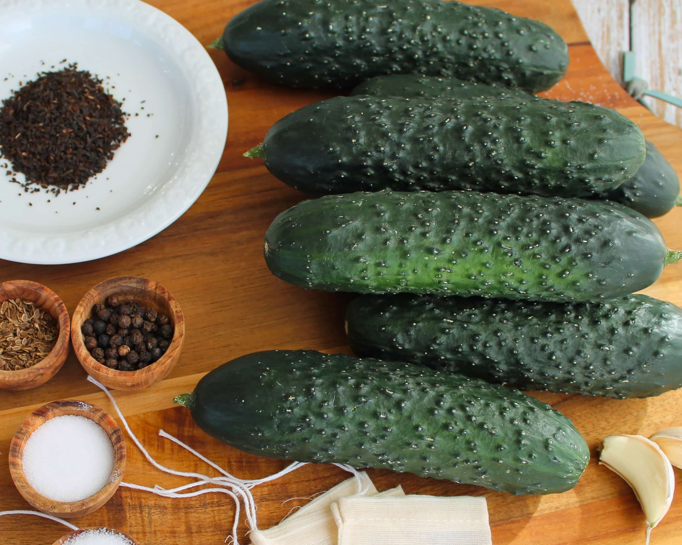 Einlegegurken mit Gewürzen wie Pfeffer, Dill und Salz auf Holzbrett