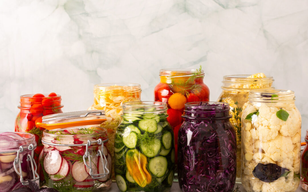 Verschiedene fermentierte Gemüsesorten in Gläsern wie Gurken, Karotten, Kohl und Radieschen