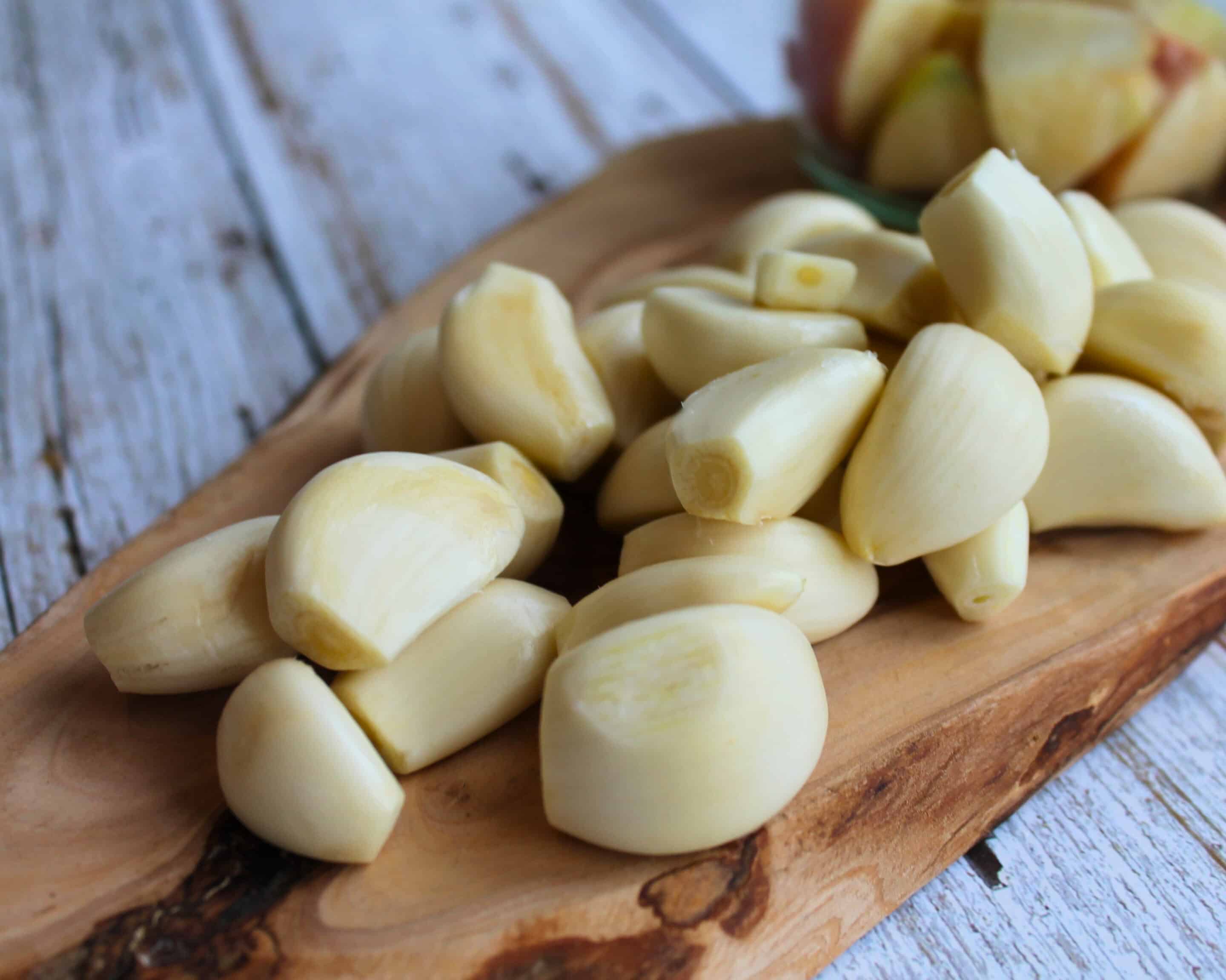 Geschälte Knoblauchzehen auf einem Holzbrett als Vorbereitung für fermentierten Knoblauch