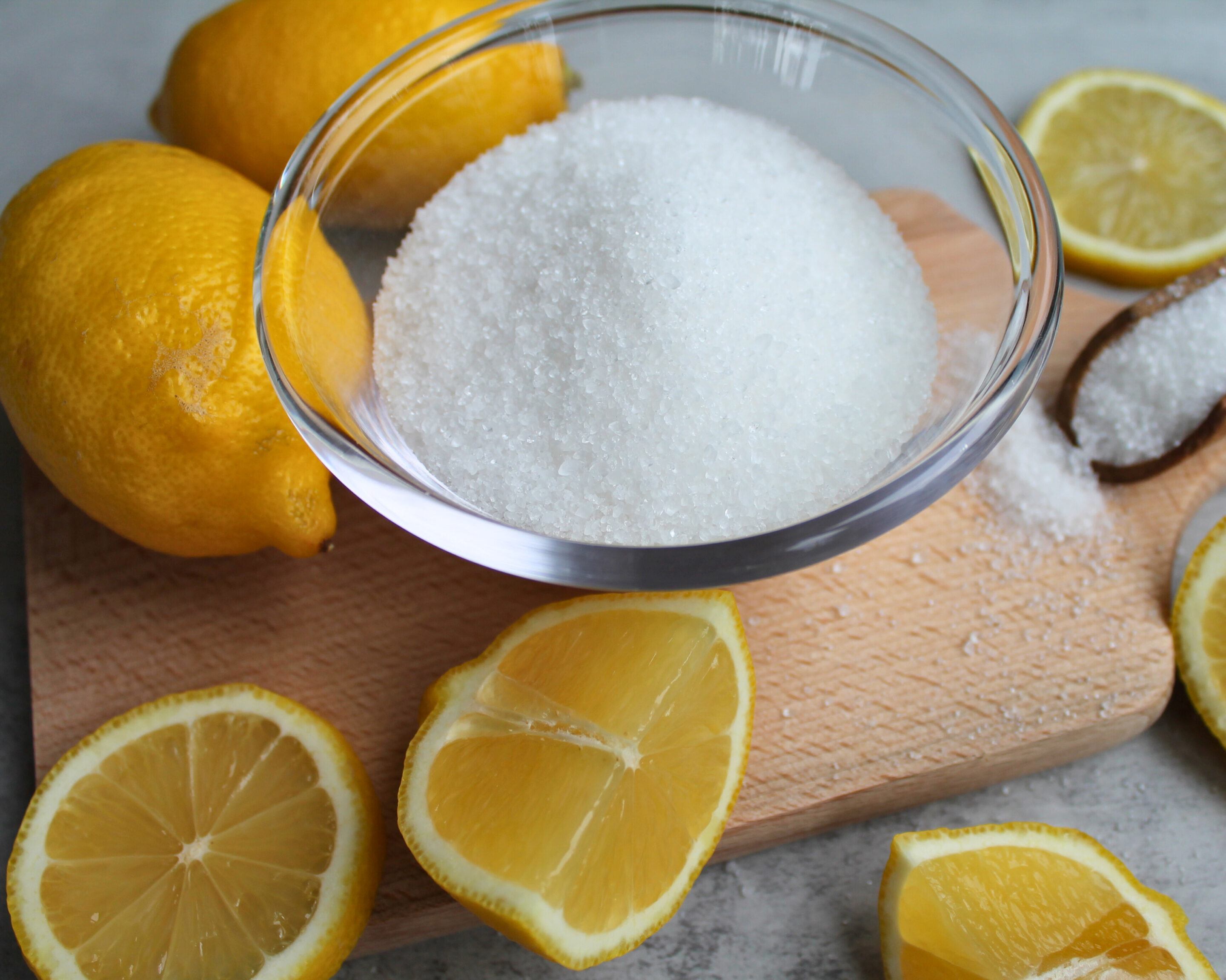 Zucker in einer Glasschale mit frischen Zitronen als Zutaten für die Gelierung von Marmelade und Gelee.