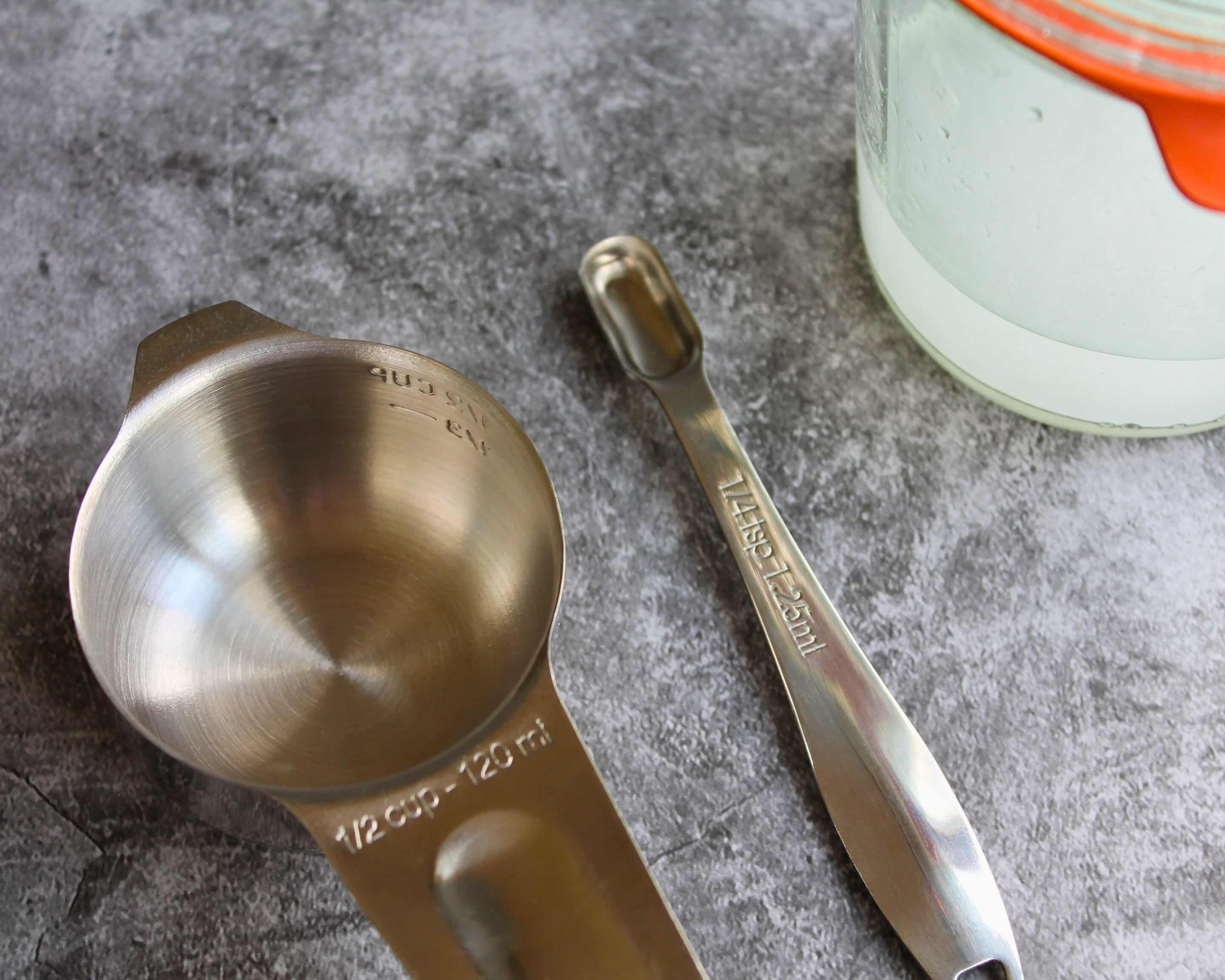 Amerikanische Messlöffel – 1/2 Cup und 1/4 Teaspoon – neben Weckglas mit Calciumlösung für Pomona's Universal Pectin Rezept