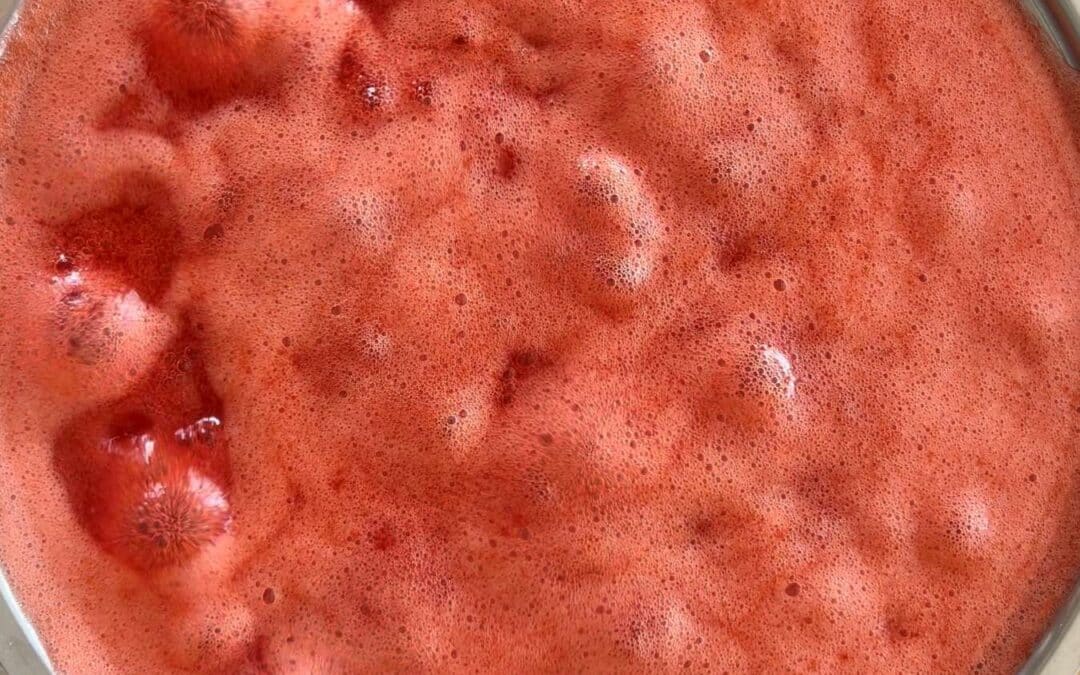 Kochende Erdbeerkonfitüre in einem Topf mit rotem Schaum von oben
