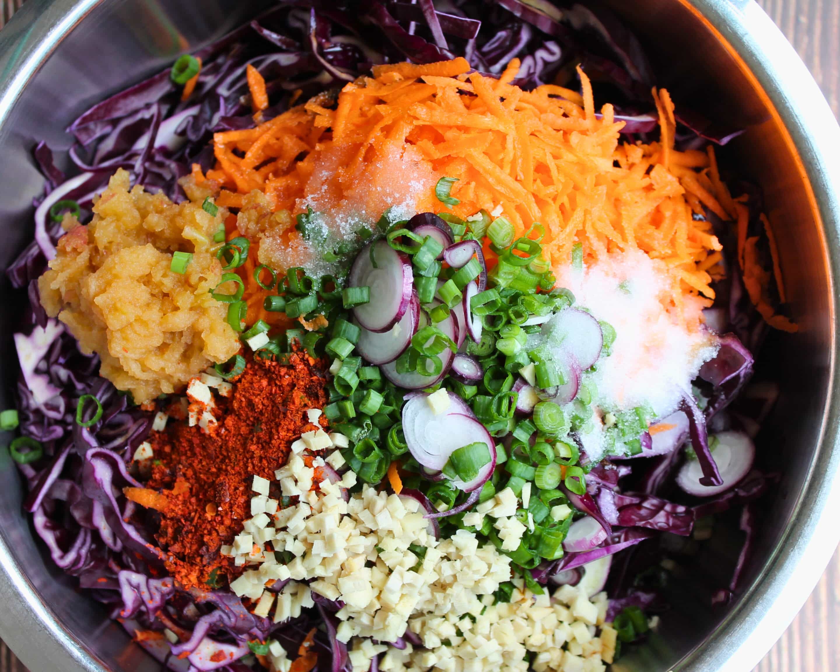 Rotkohl, Karotten, Frühlingszwiebeln, Ingwer, Knoblauch und Kimchi-Gewürze für Rotkohl-Kimchi in einer Schüssel