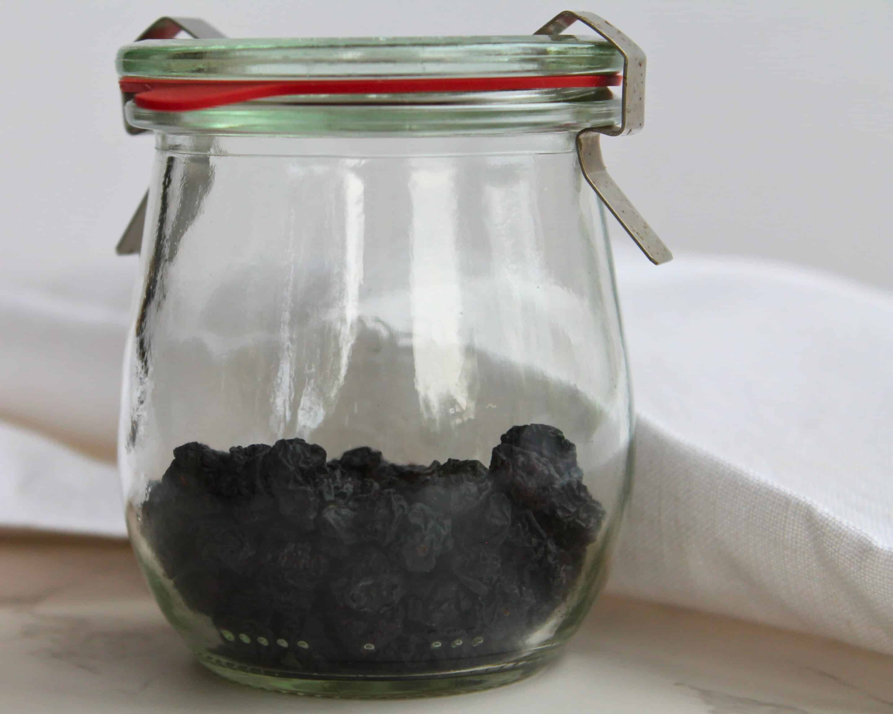 Getrocknete Blaubeeren in einem Weckglas mit rotem Gummiring auf hellem Untergrund