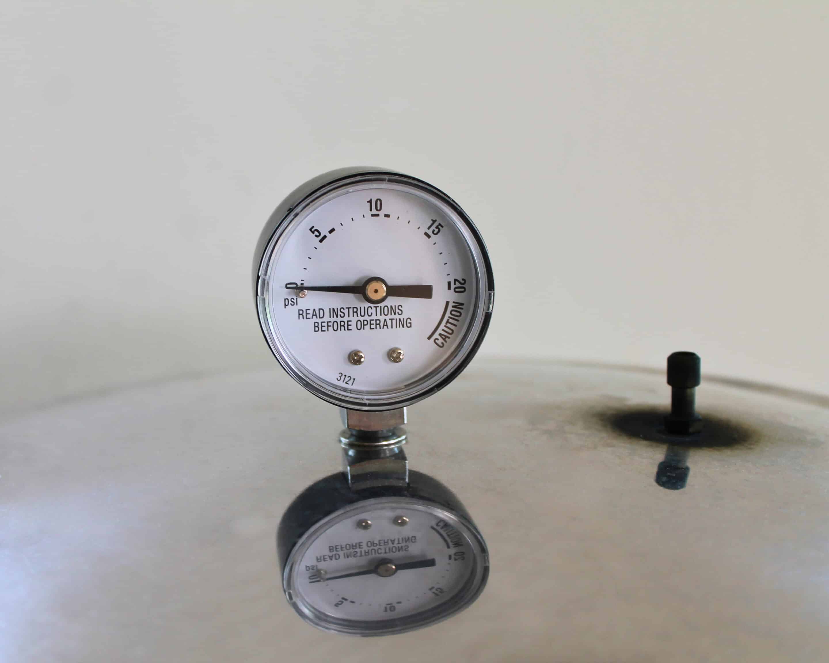 Manometer eines Pressure Canners mit PSI-Skala und Caution-Bereich, daneben der Überdruckregler auf dem Deckel