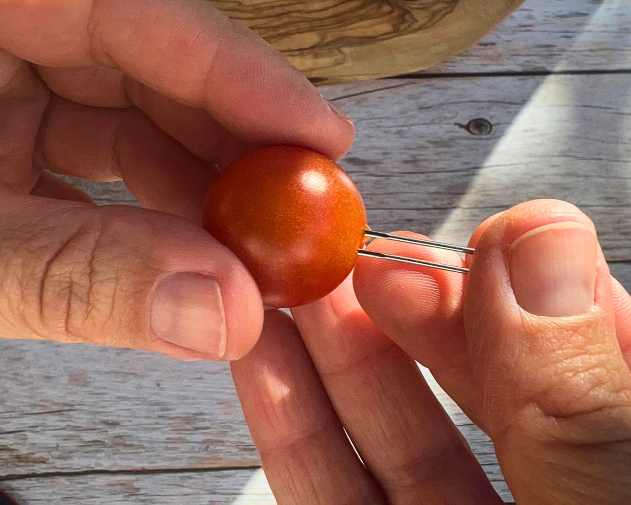 Cocktailtomate wird mit einer Nadel angepikst, damit die Salzlake durch die Schale ins Innere gelangt